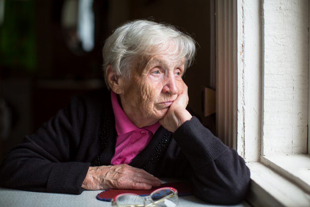 Verdrietige oude vrouw aan raam